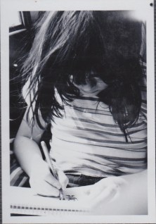 black and white photo of girl drawing in the car