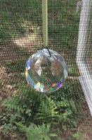 Chunky faceted crystal suncatcher in front of window screen