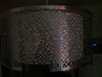 Hanging metal lamp shade with circle reflecting colored lights.