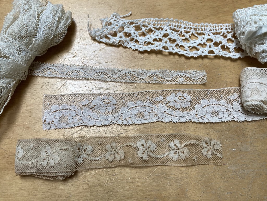 Four samples of lace: two abstract and two with realistic designs (cloverleafs and flowers).